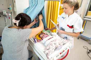 Foto van moeder die baby sondevoeding geeft onder begeleiding